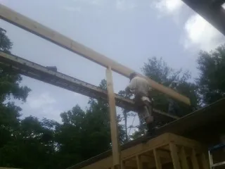 Carpenter setting a ridge beam over a new addition frame — Ice Dam Removal by Roofing Brothers in Clarendon
