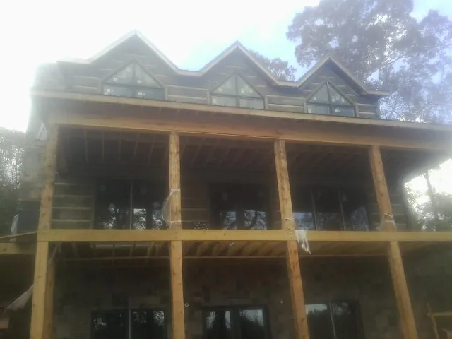 Dormers and porch framing on a large log home under construction — Roof Coating work by our crew in Clarendon