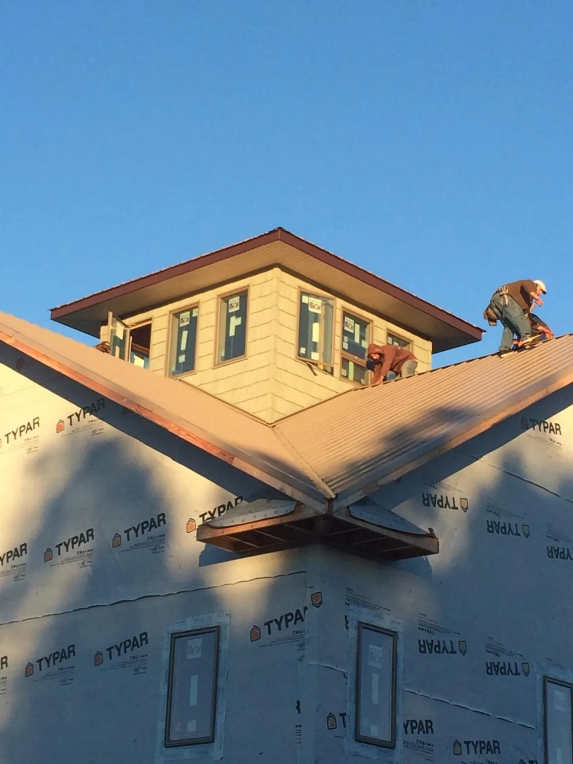 Roofers working around a rooftop cupola on a new metal roof at sunset — Roof Waterproofing in Clarendon by Roofing Brothers